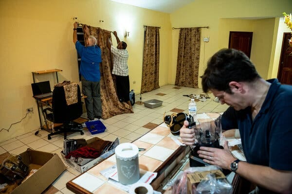 Colonel Aaron helps Mr. Khan hang curtains while Matthew Hellman assembles a blender. Colonel Aaron helps Mr. Khan hang curtains while Matthew Hellman assembles a blender.