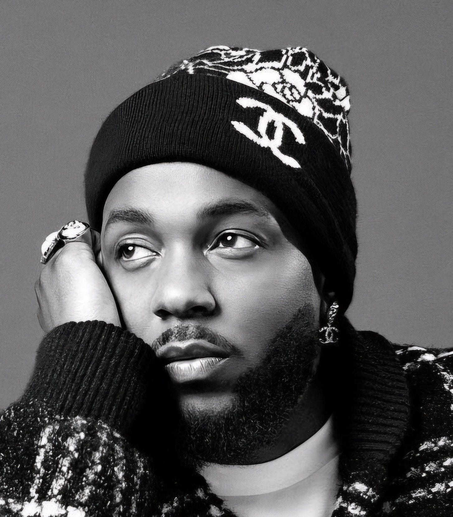 Kendrick posing for Chanel with a beanie and his palm resting on his face