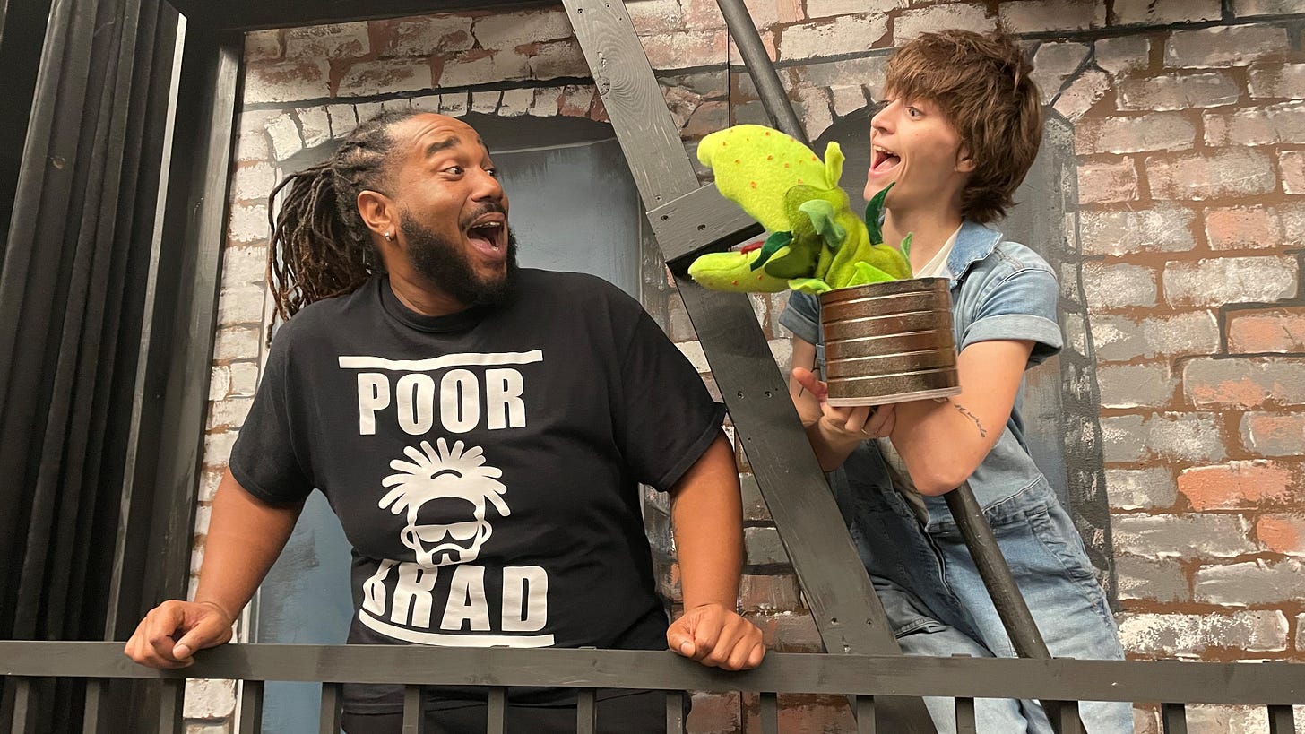 Two actors posing with a puppet of a carnivorous plant Two actors posing with a puppet of a carnivorous plant