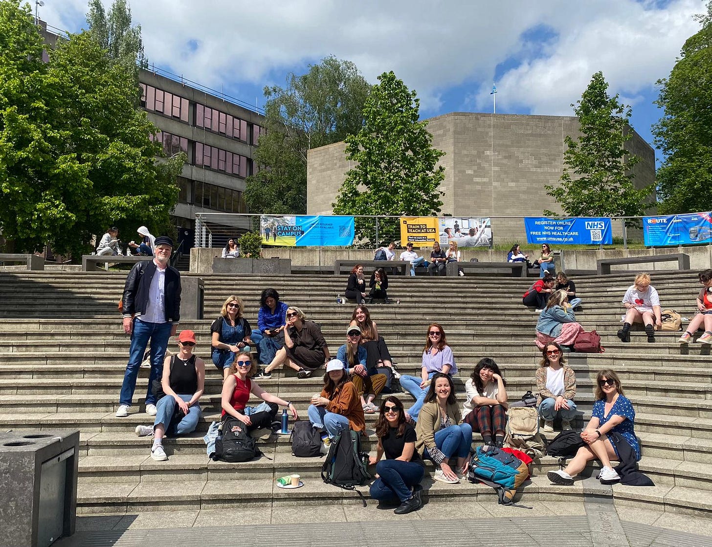 A group of people sitting on the steps at the campus of the University of East Anglia