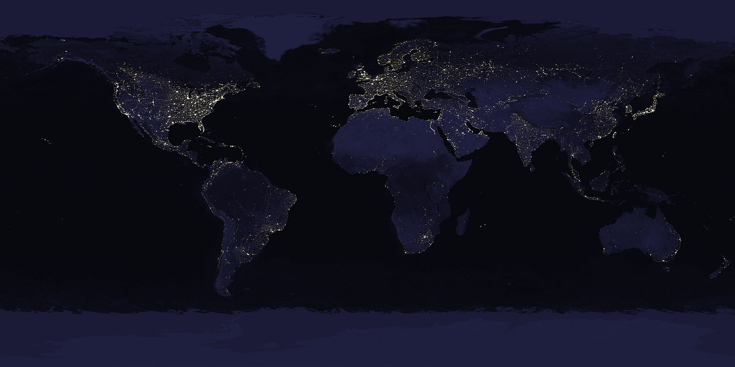 A map of the Earth's surface, showing the continents in navy blue against dark blue oceans. The city lights across the surface are lit up in yellow.