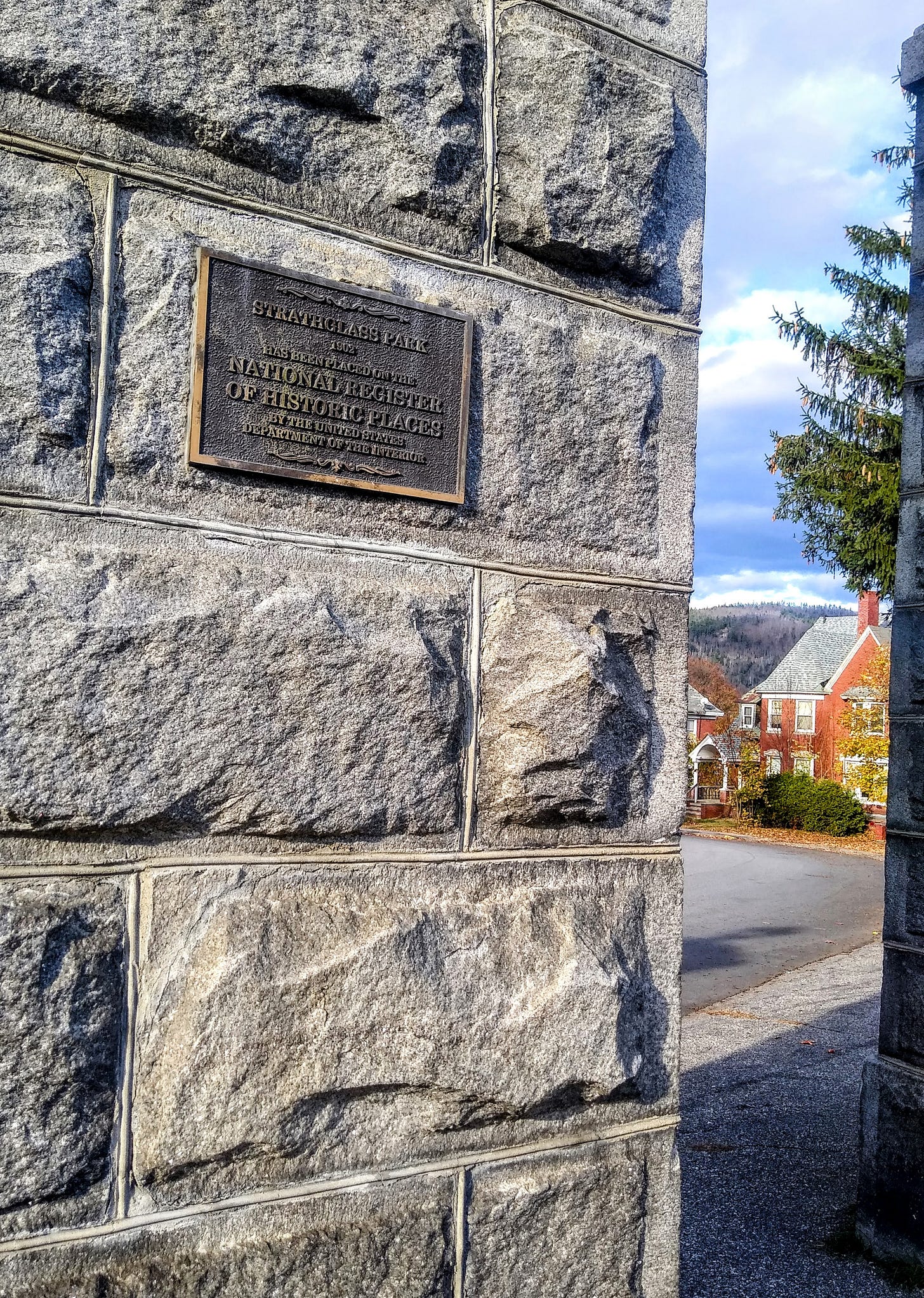 The stone entryway to Strathglass park, you can see a portion of a house through the entrance