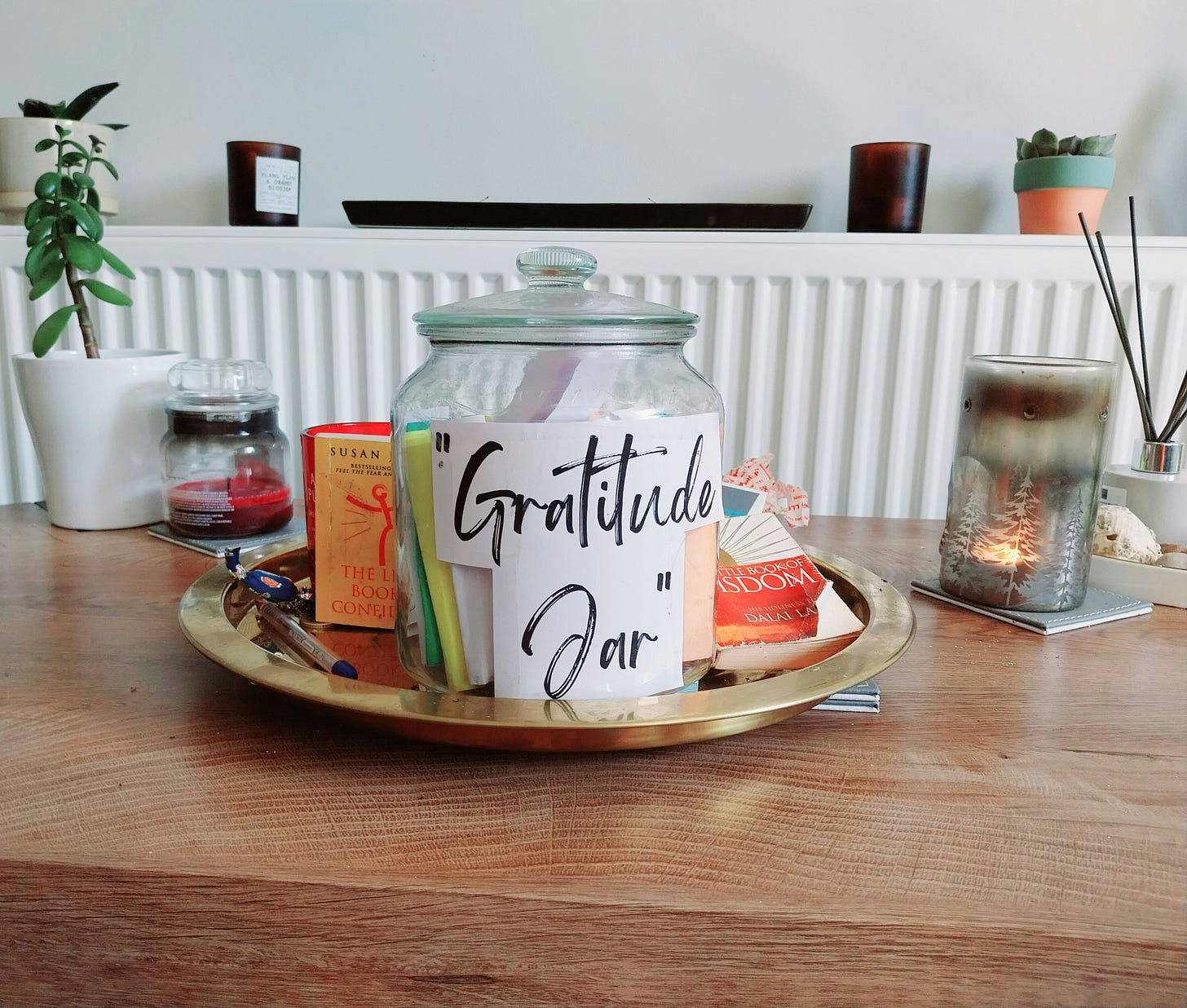 glass jar labeled "gratitude jar" on a wood table