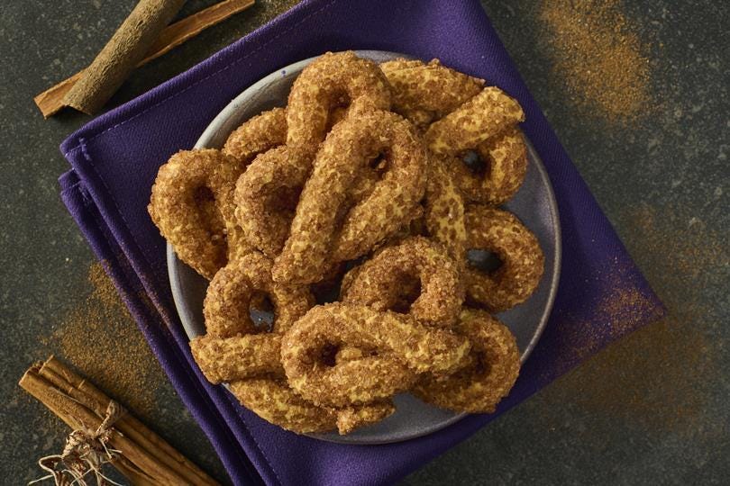 all butter cinnamon knots in a pile on white plate on a purple placement