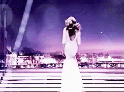 Julia Roberts stands in a white gown overlooking a skyline, turning around in close up with a bright smile.