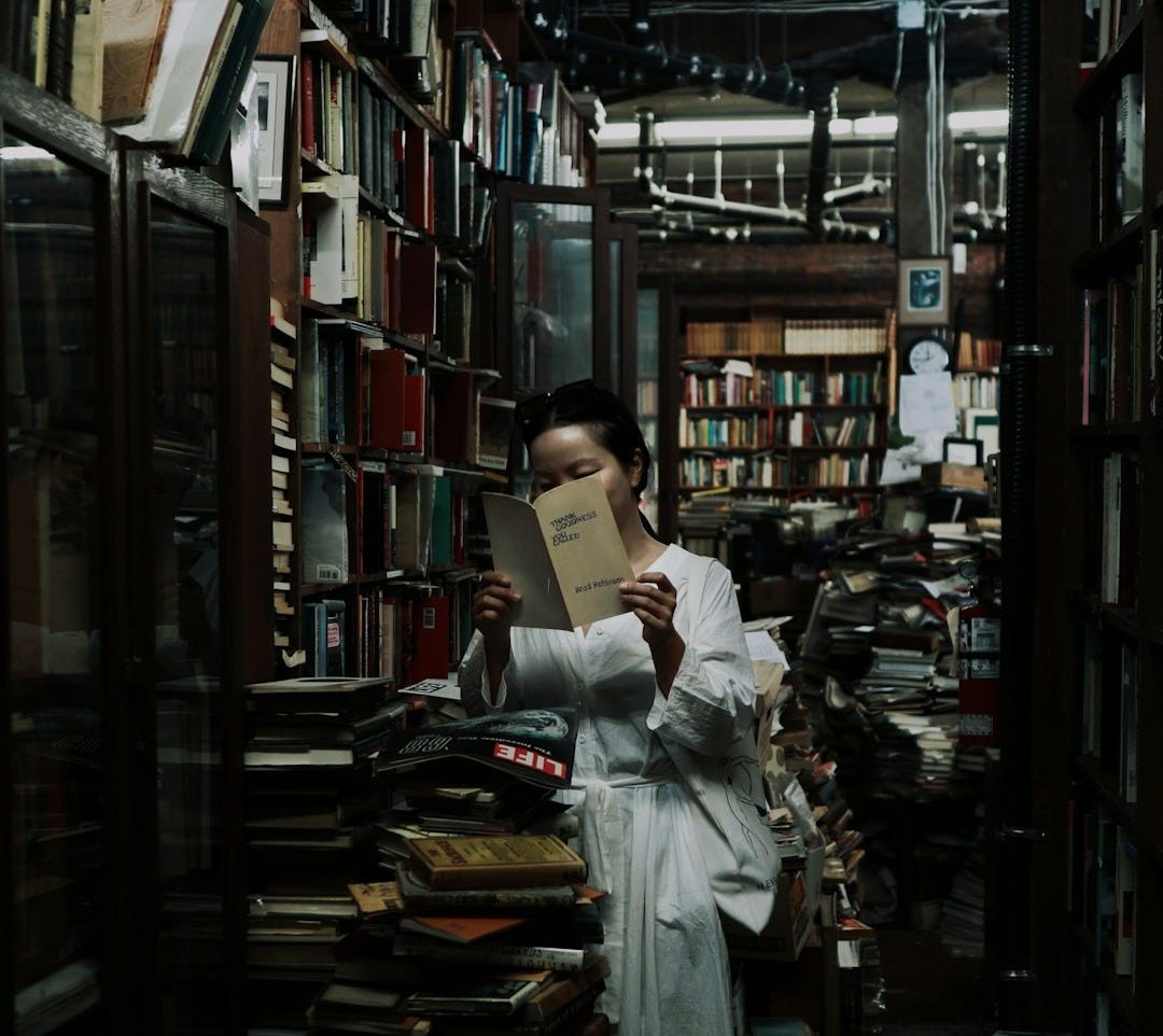 woman in white long sleeve shirt reading book in library