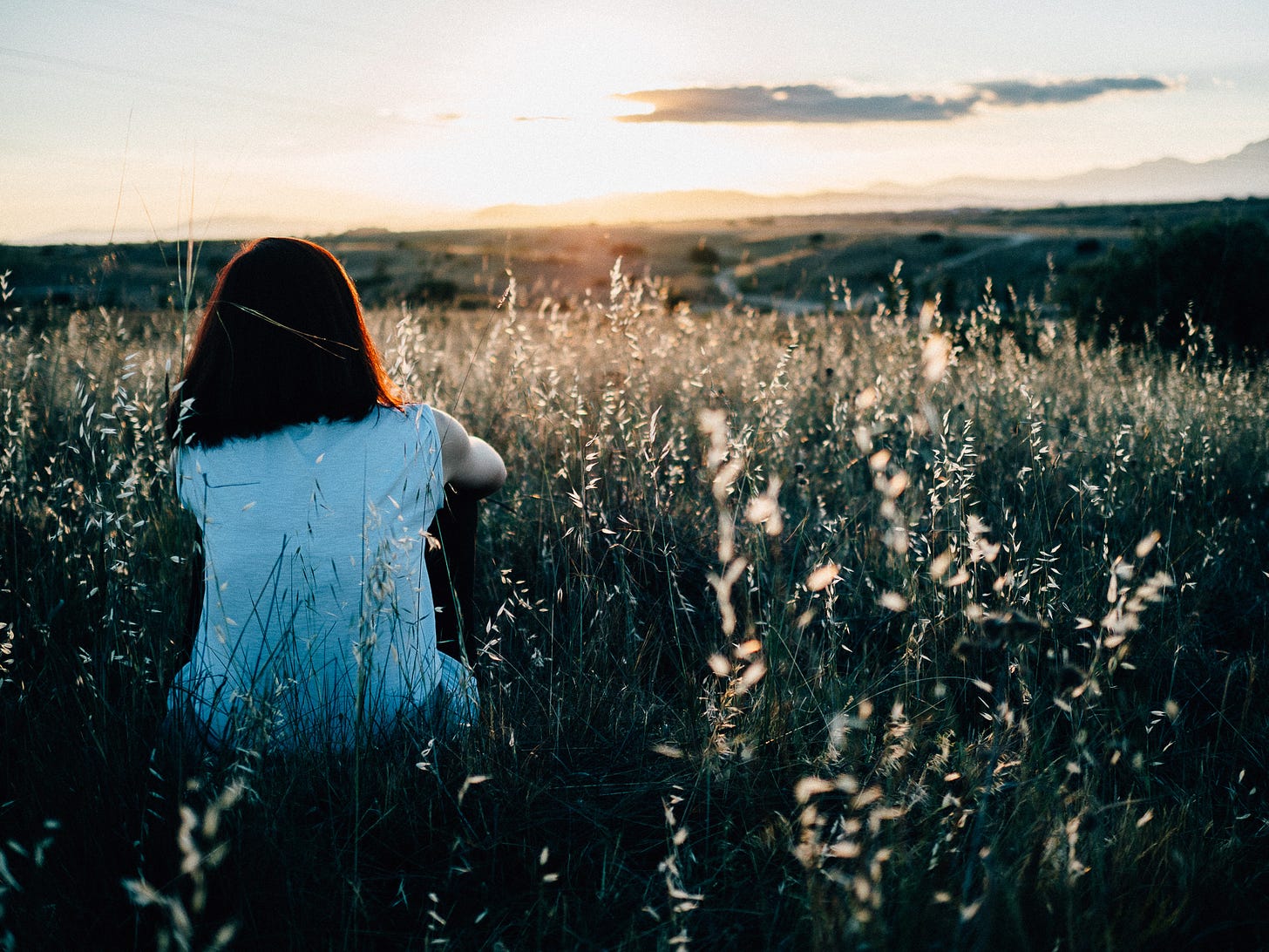 woman sitting alone in a field. Woman wondering, thinking. God's grace woman sitting alone in a field. Woman wondering, thinking. God's grace