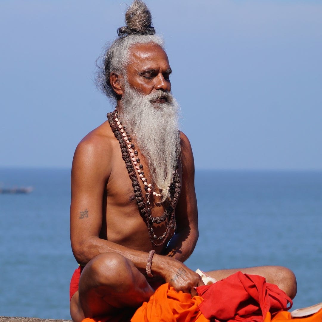 topless man sitting on brown sand near body of water during daytime topless man sitting on brown sand near body of water during daytime