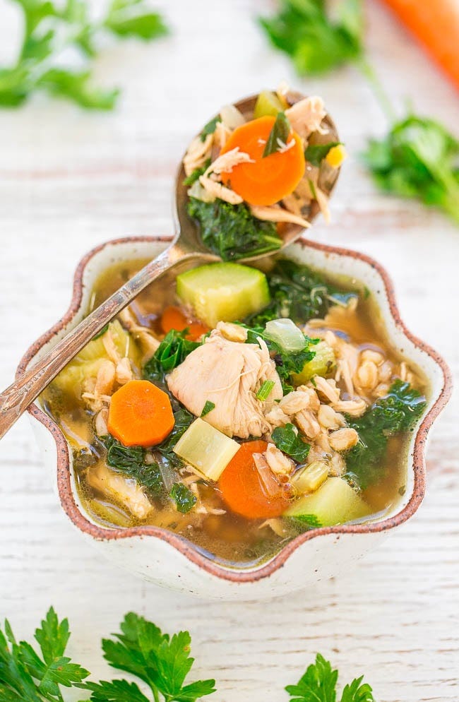 a bowl of chicken vegetable soup with a spoon resting on the edge. a bowl of chicken vegetable soup with a spoon resting on the edge.