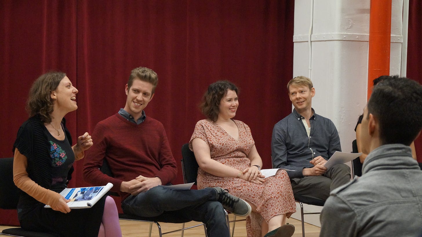 Four people sit in a row of chairs facing an audience