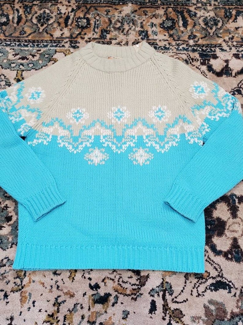 May include: A blue and beige knitted sweater with a white snowflake pattern.