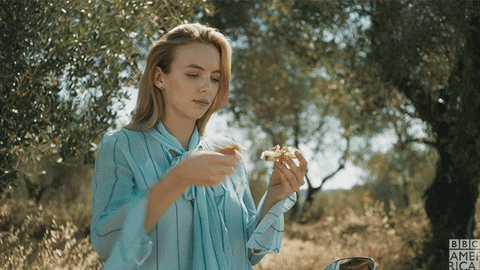 This may contain: a woman eating food in the middle of an olive grove This may contain: a woman eating food in the middle of an olive grove
