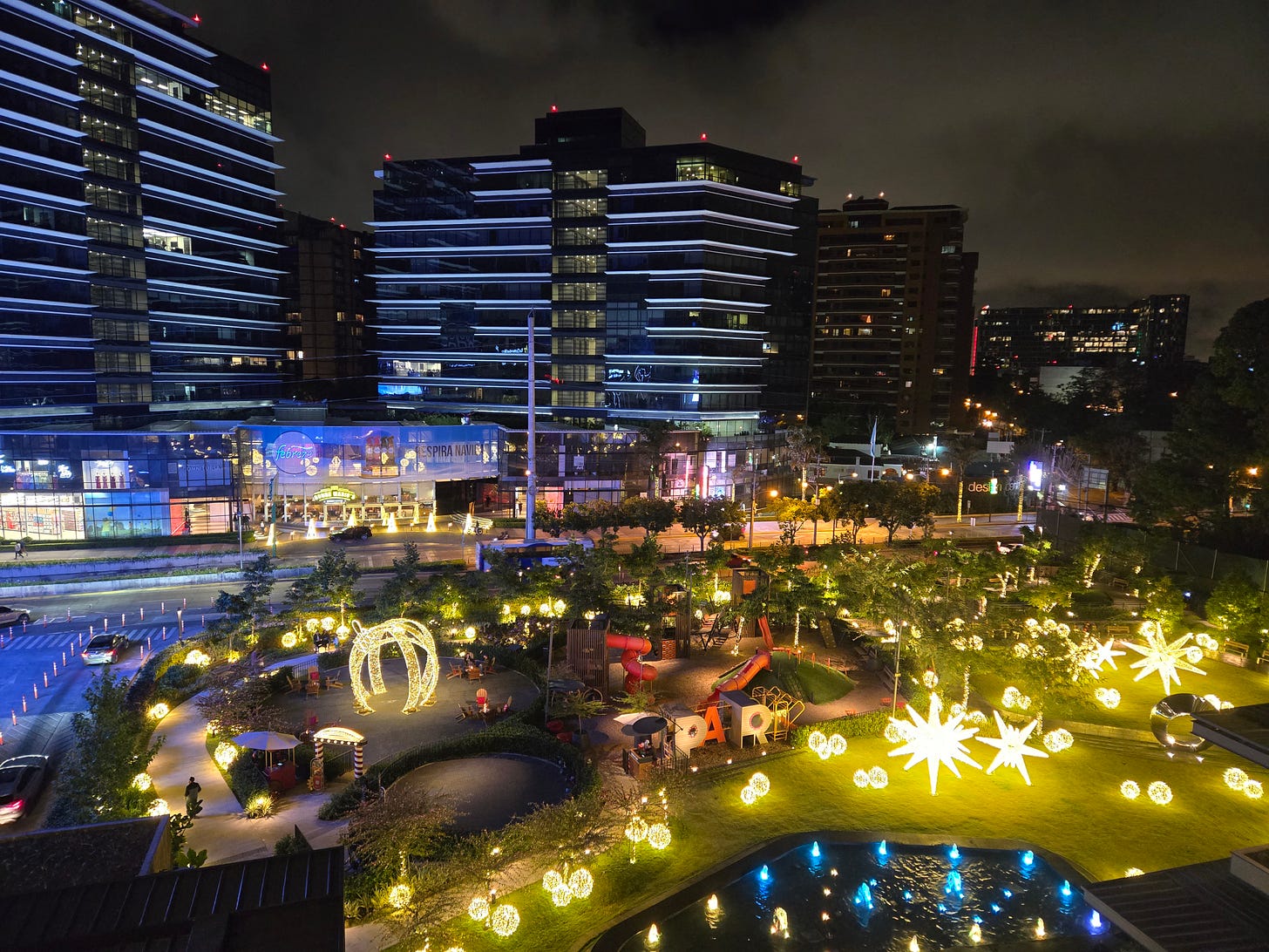 A little park in the foreground, with lots of Christmas lights and a playground, and office towers in the background. A little park in the foreground, with lots of Christmas lights and a playground, and office towers in the background.
