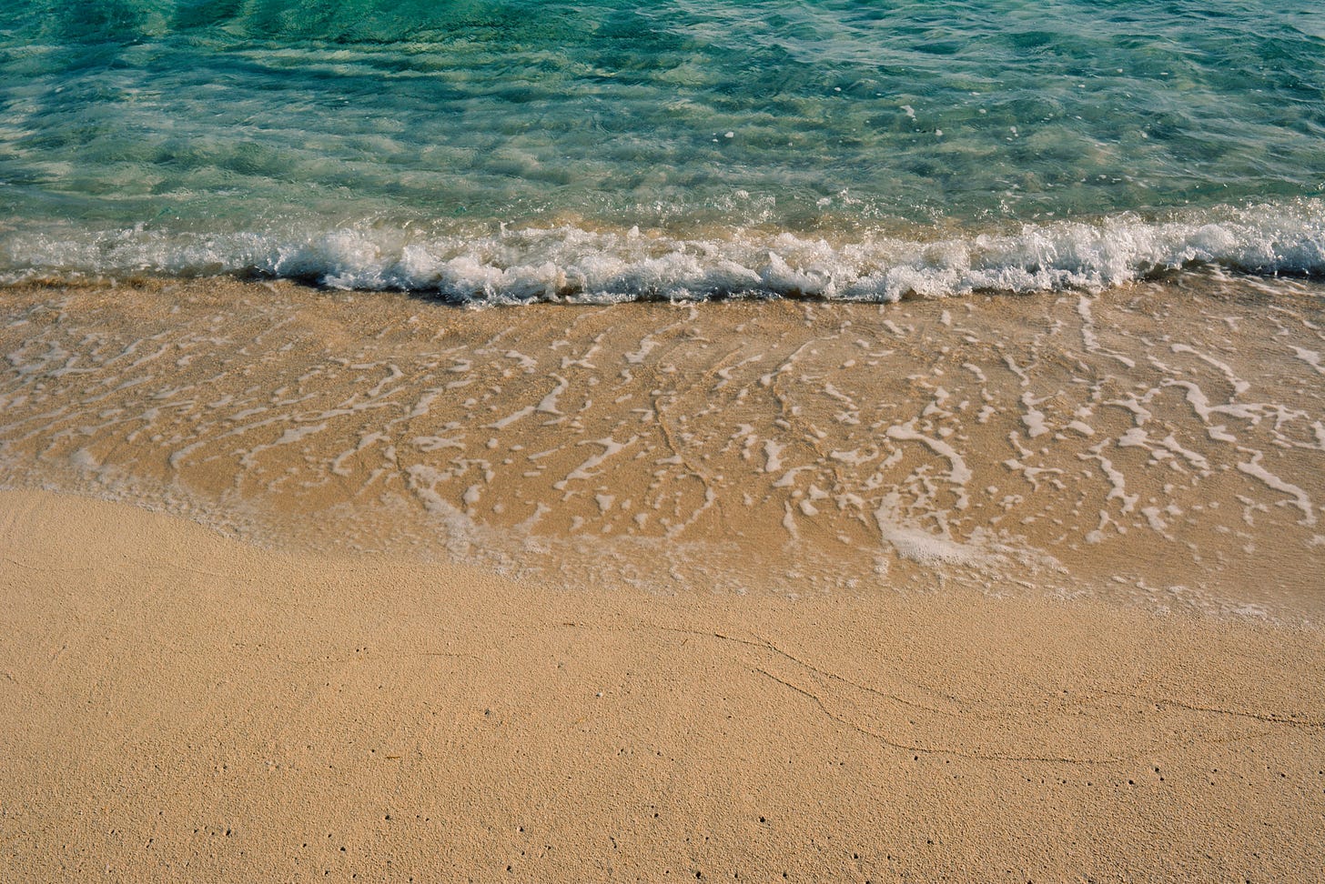 Gentle waves lapping against a sandy beach, with clear blue water reflecting sunlight, creating a serene coastal scene. Gentle waves lapping against a sandy beach, with clear blue water reflecting sunlight, creating a serene coastal scene.