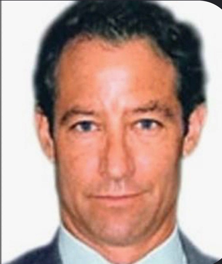 Middle-aged man with dark hair in a suit.