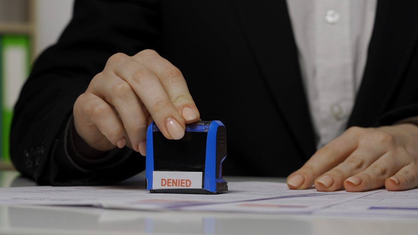 A woman marking a paper with a "denied" stamp A woman marking a paper with a "denied" stamp