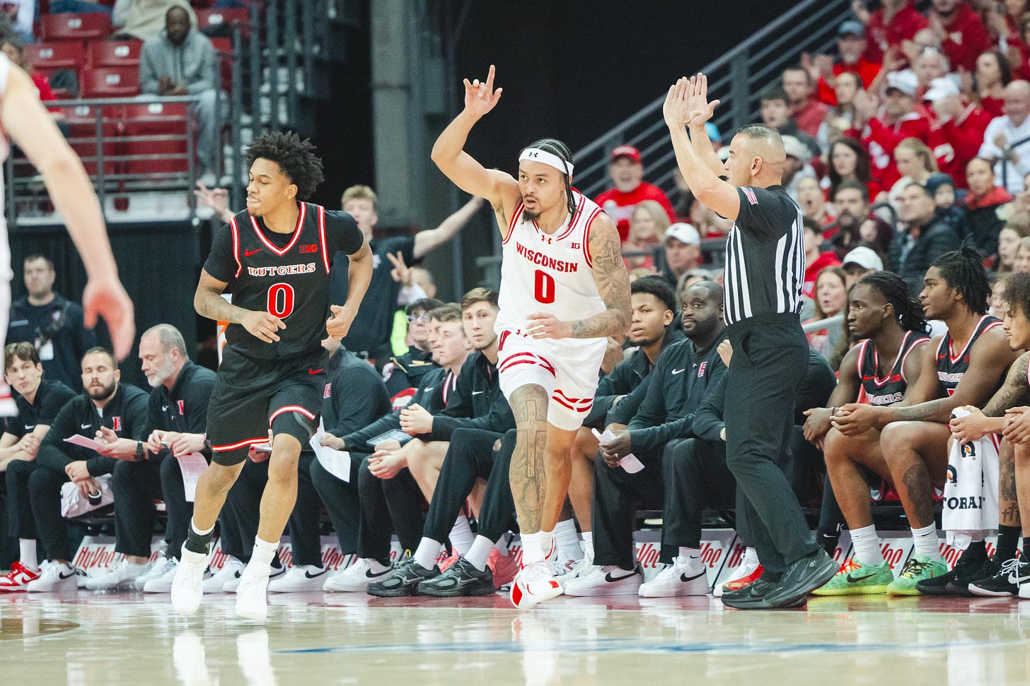 Wisconsin basketball guard Braden Carrington points his finger up toward the ceiling in celebration while beginning to run back up the court in transition