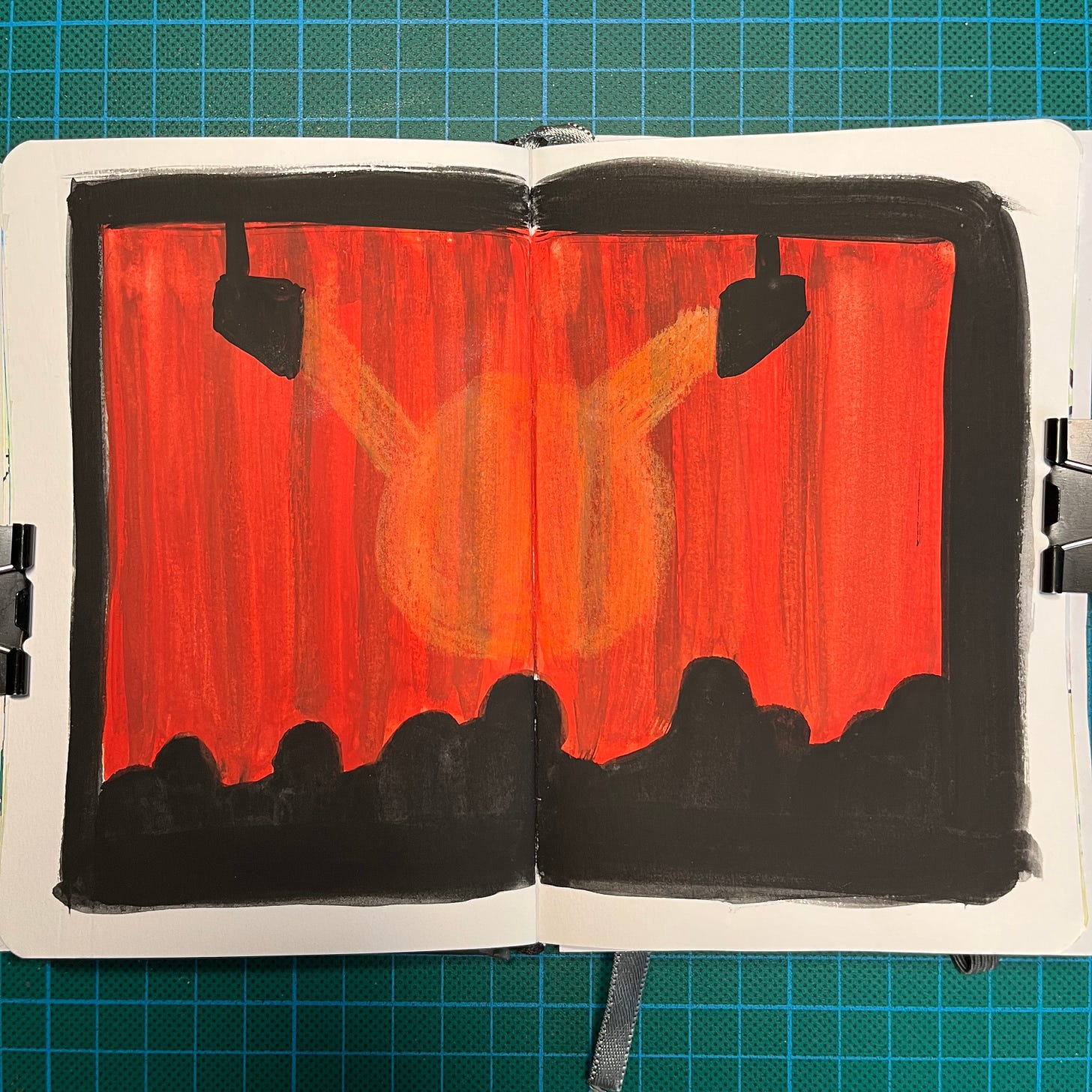 Posé sur mon tapis de découpe, mon sketchbook ouvert sur la double-page où j'ai fait le dessin du Jour 24 : les silhouettes de spectateurs devant un rideau rouge fermé et des spots. Posé sur mon tapis de découpe, mon sketchbook ouvert sur la double-page où j'ai fait le dessin du Jour 24 : les silhouettes de spectateurs devant un rideau rouge fermé et des spots.