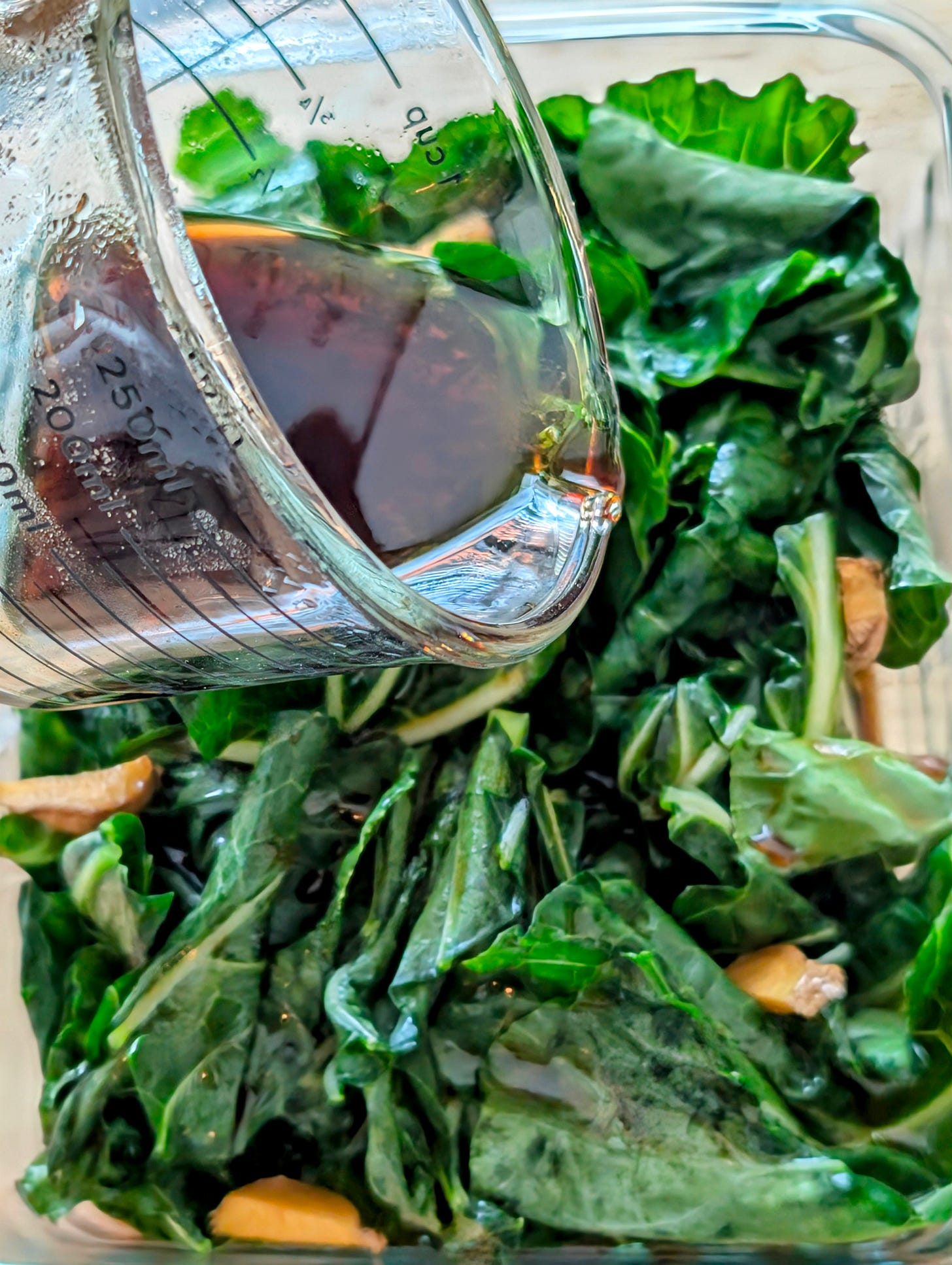 Soy sauce brine being poured over chopped collard greens.