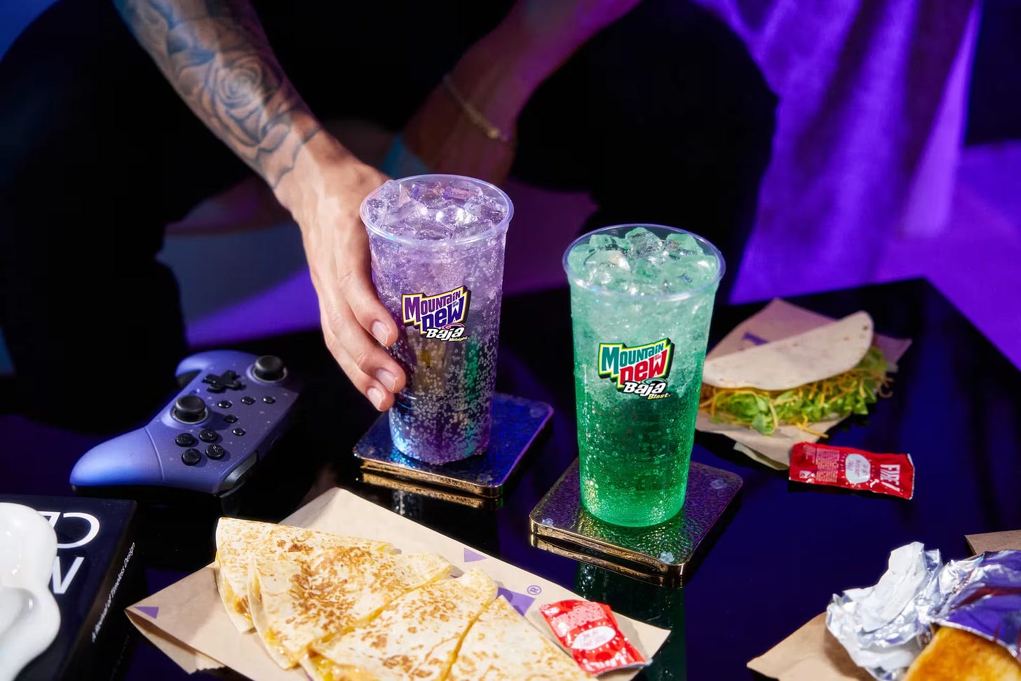 Advertising photo with Taco Bell food on a coffee table next to a Baja Blast and the new Baja Midnight