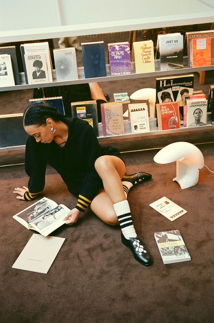 This may contain: a woman sitting on the floor in front of books