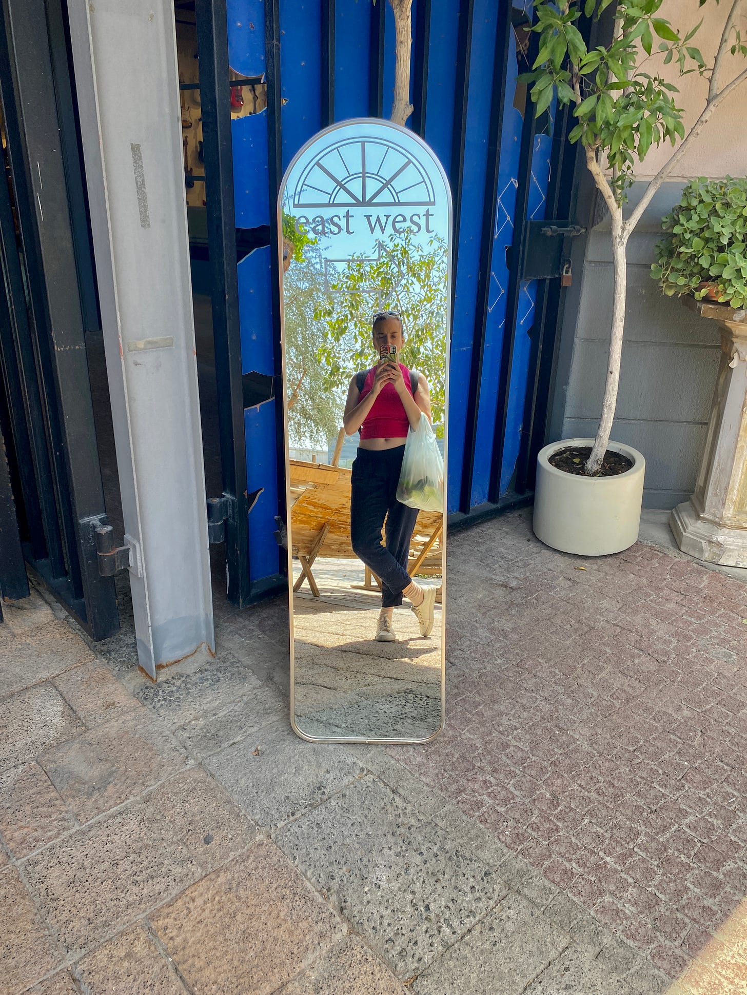 A self portrait in a mirror which points both east and west with a bright blue screen behind.