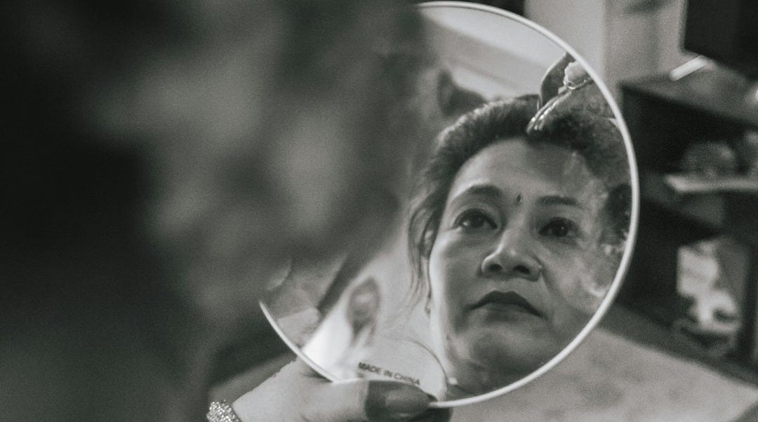 grayscale photo of girl in white shirt holding mirror
