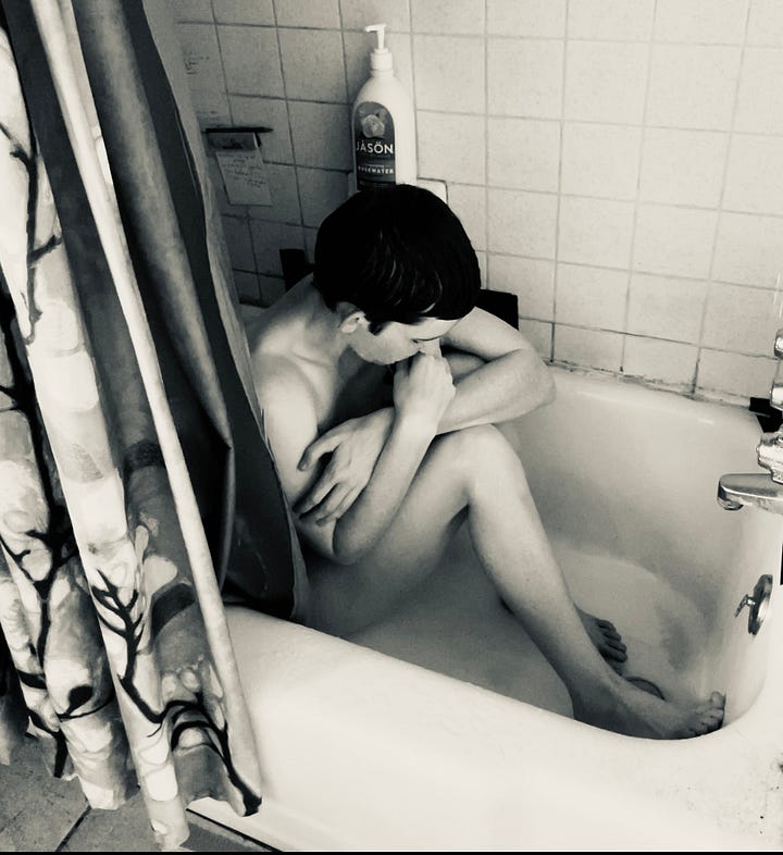A series of four black and white self-portraits of a person sitting in a bathtub alone. They are covering themself, curled into a ball. The sense is solitary and lonely.