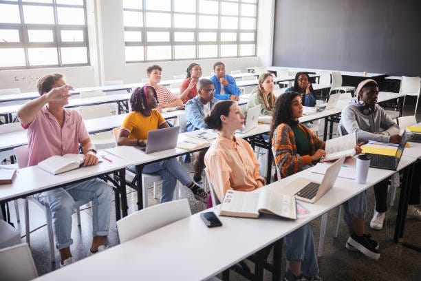 Diverse young college students sitting at tables during a class together Diverse young college students sitting at tables during a class together
