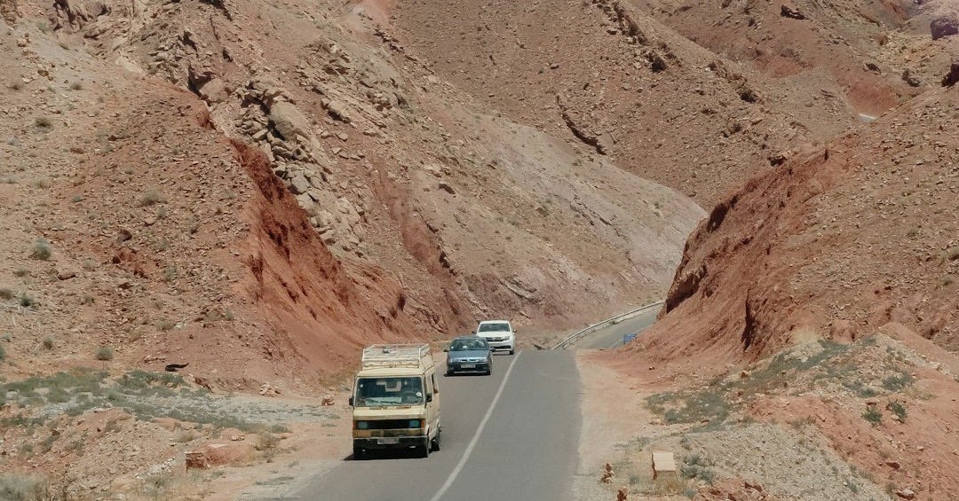 Vehicles travel on a road through a rocky, mountainous landscape.