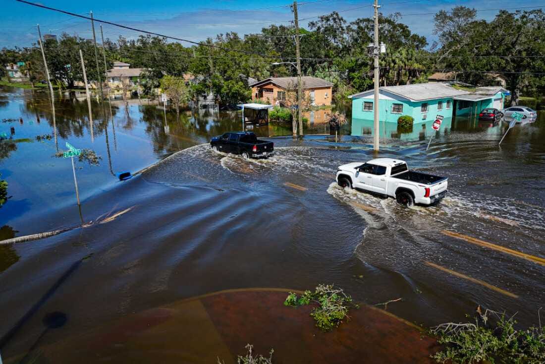 A car drives through a flooded neighborhood