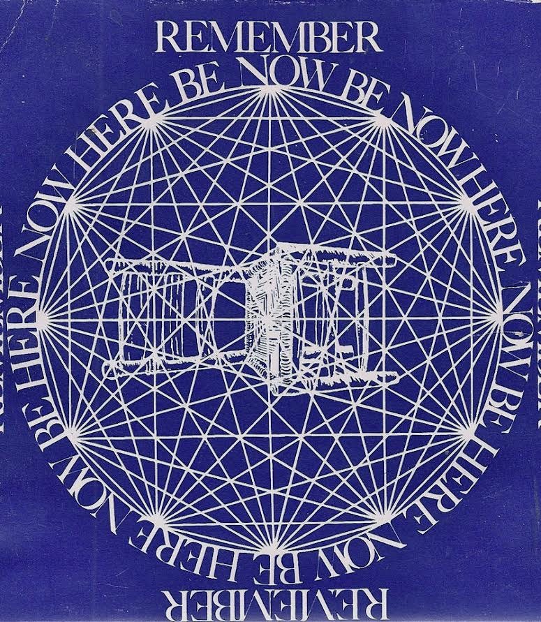 Pictured is white sacred geometry circle overlay of a side chair lying horizontal. The Title “Be Here Now” is written circular to the sacred geometry and equidistance on all four points of the book with the word “Remember” at the top and bottom of the page all written in the same font. The page is a dark blue color, and there are 12 different convergent points of the geometrical pattern that create bright white vertices.