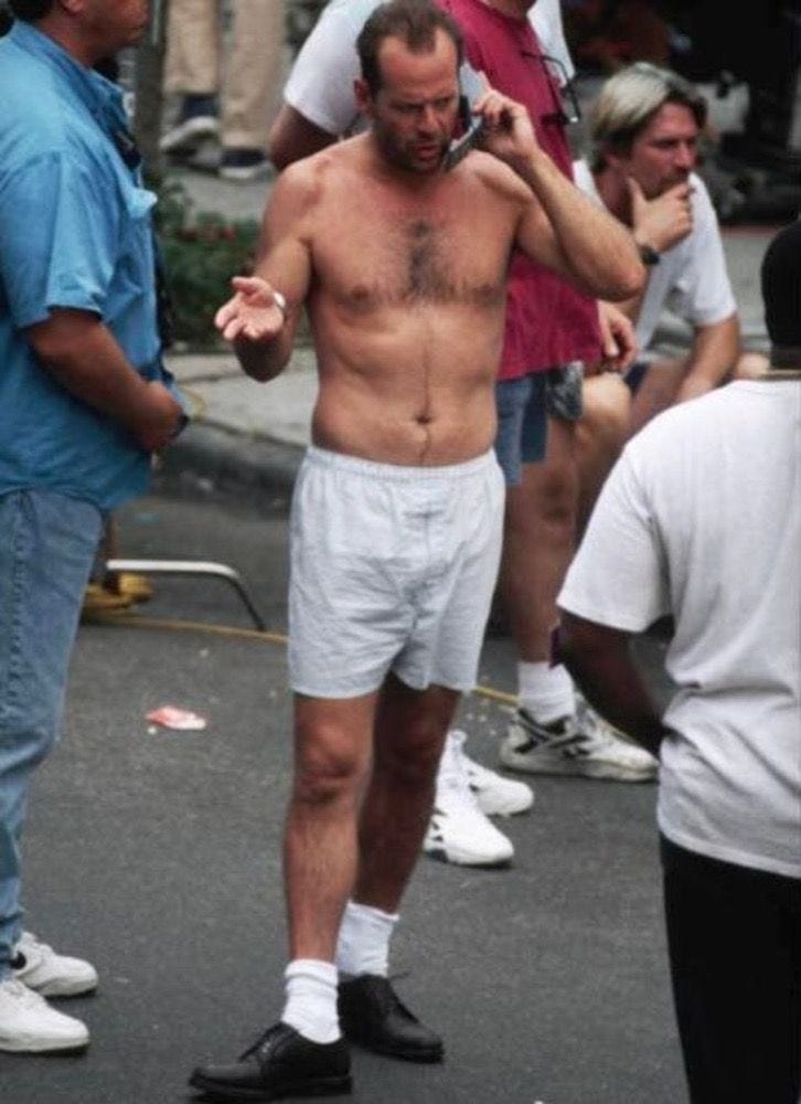 This may contain: a shirtless man talking on his cell phone while standing in the middle of a street