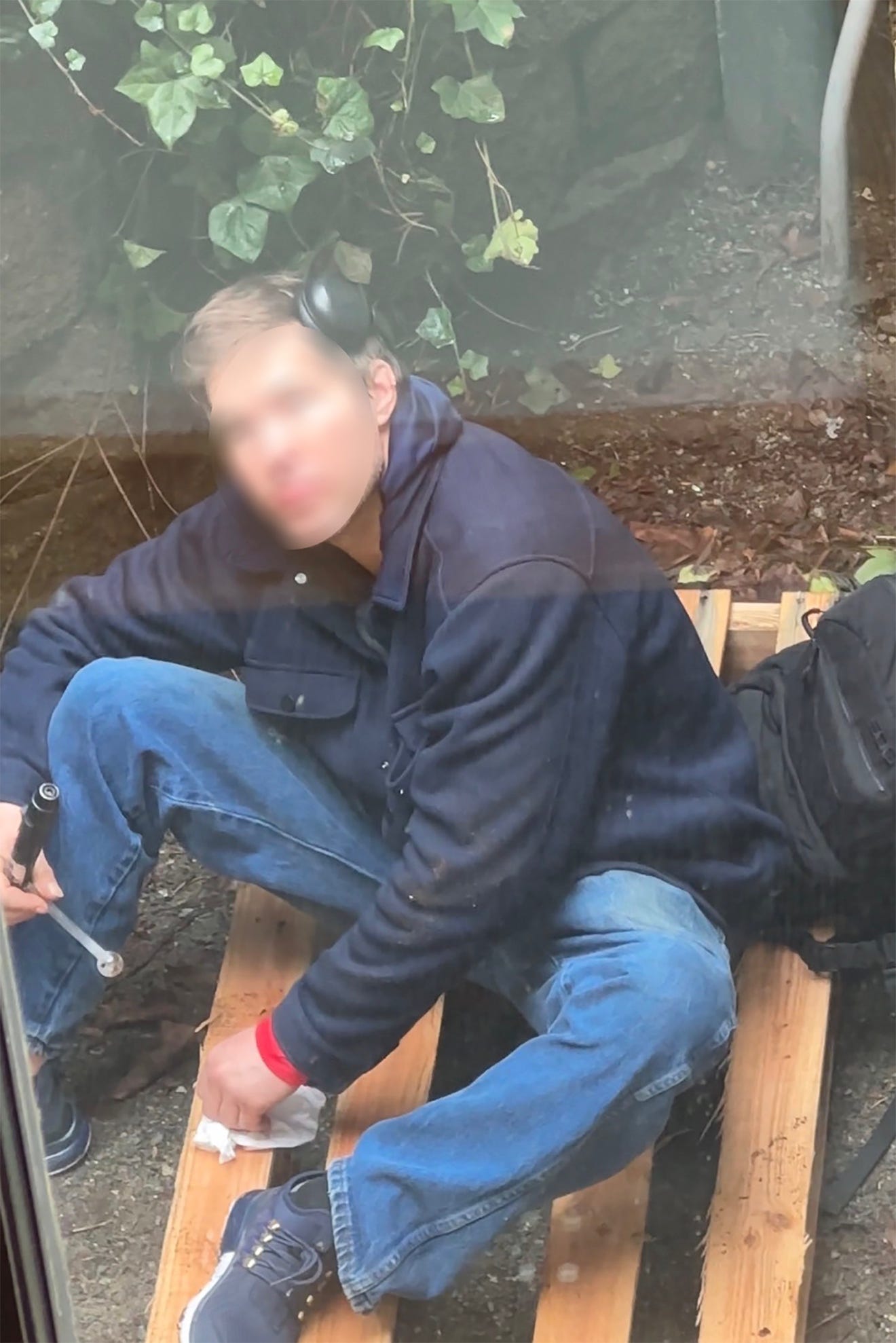 A person sitting on a pallet

Description automatically generated