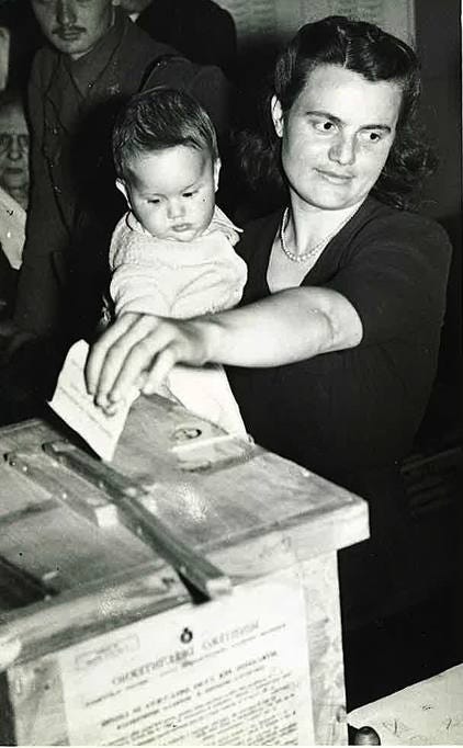 Donna con bambino che inserisce la scheda elettorale nell'urna, voto storico in Italia