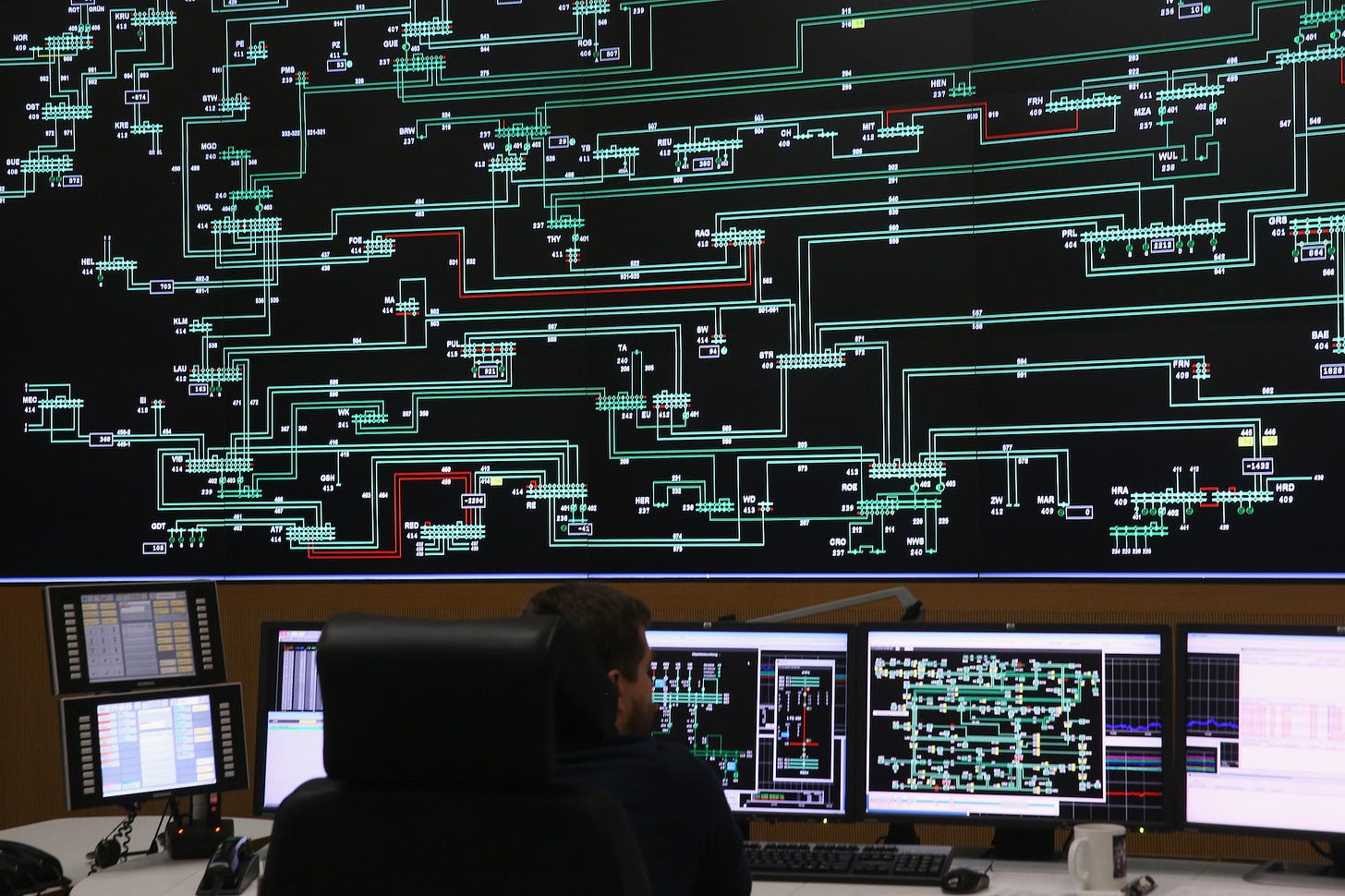  A technician monitors electricity levels in front of a giant screen.