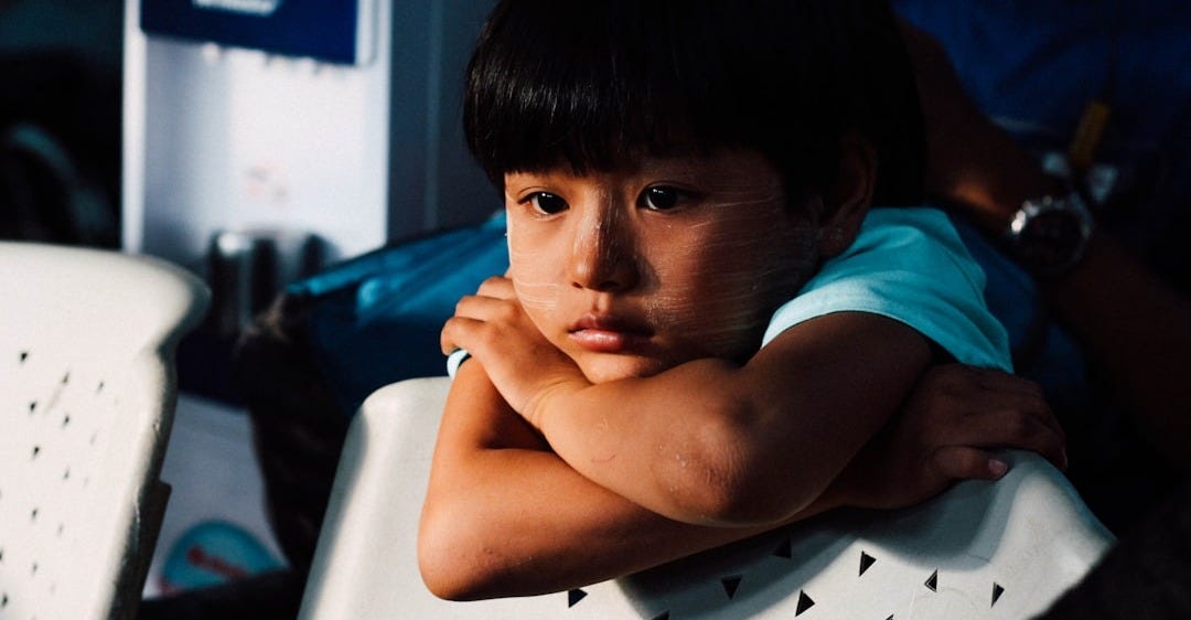 boy leaning on white chair