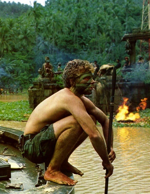 This may contain: a shirtless man sitting on top of a boat with a stick in his hand