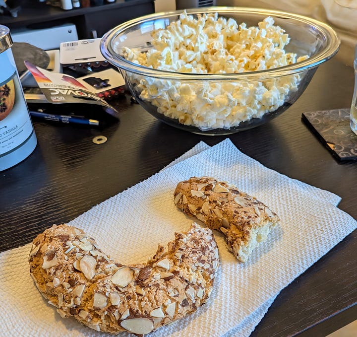 Left: A cherry strudel in parchment paper; right: a broken horseshoe cookie with a bowl of popcorn in the background.