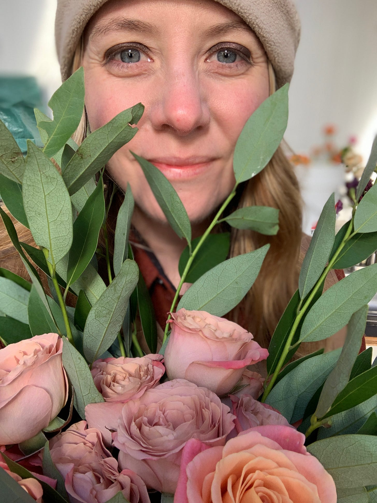 woman smiling behind a bouquet of flowers held up to her face