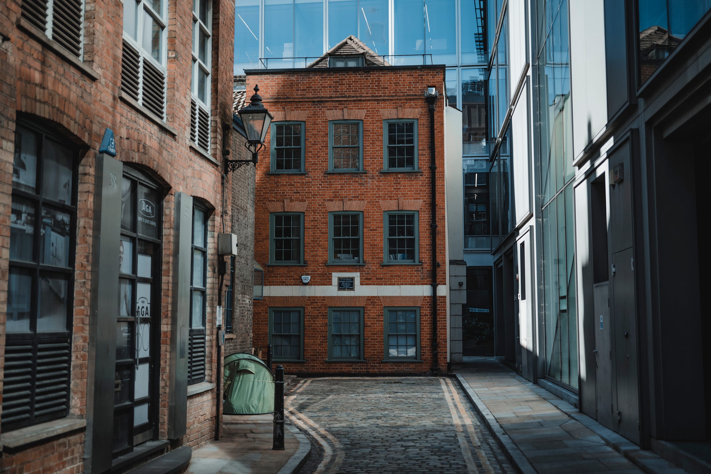 Een oud gebouw tegen een nieuw kantoorgebouw, met een tent ervoor