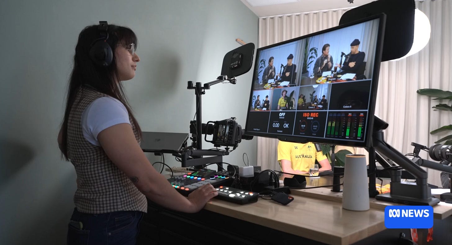 Amelia behind a screen watching a podcast recording for the podcast ListenABLE. She is wearing a checkered brown vest with a white t-shirt.