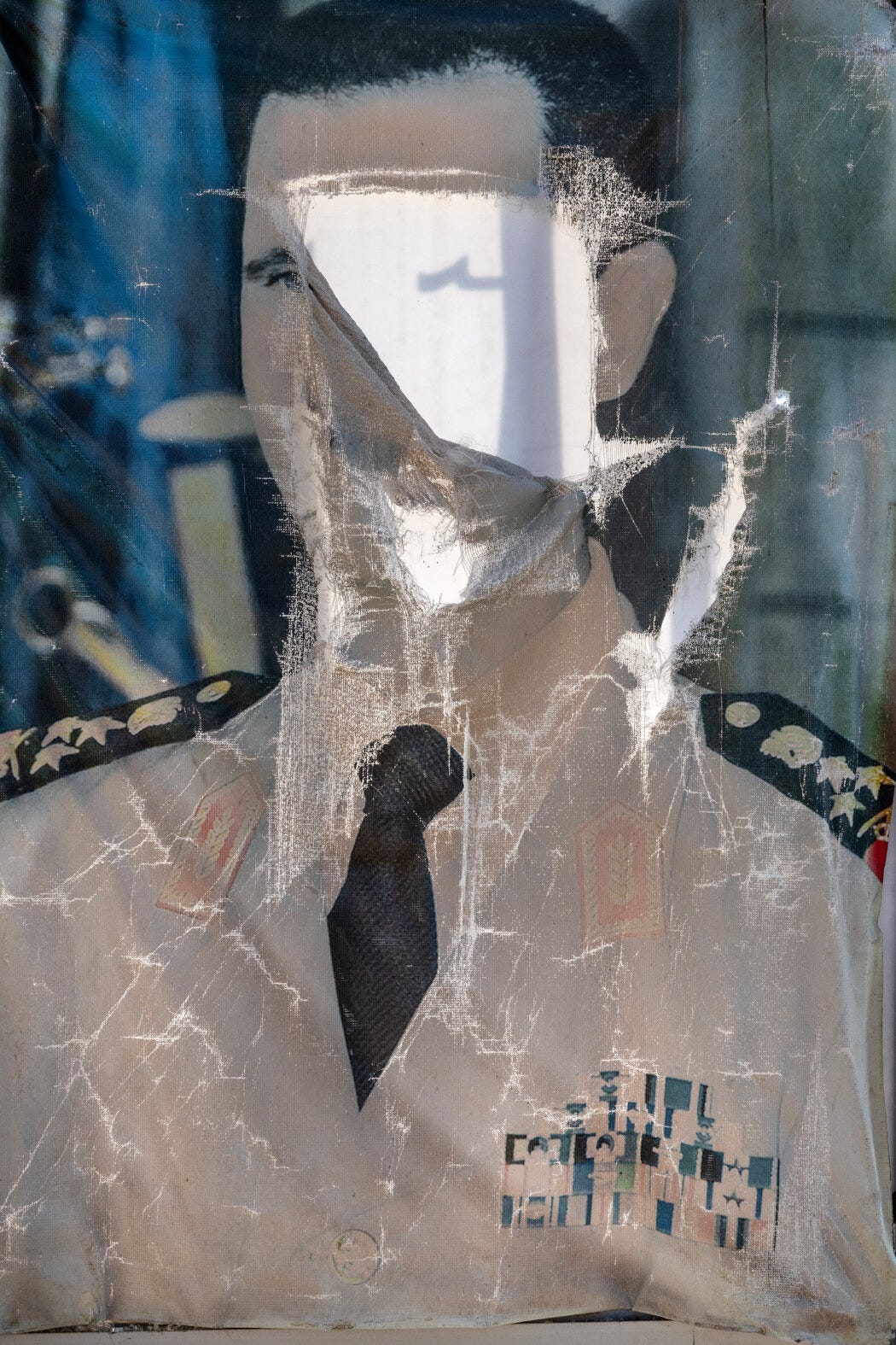 A defaced portrait of former President Bashar al-Assad of Syria, who is wearing a military uniform.