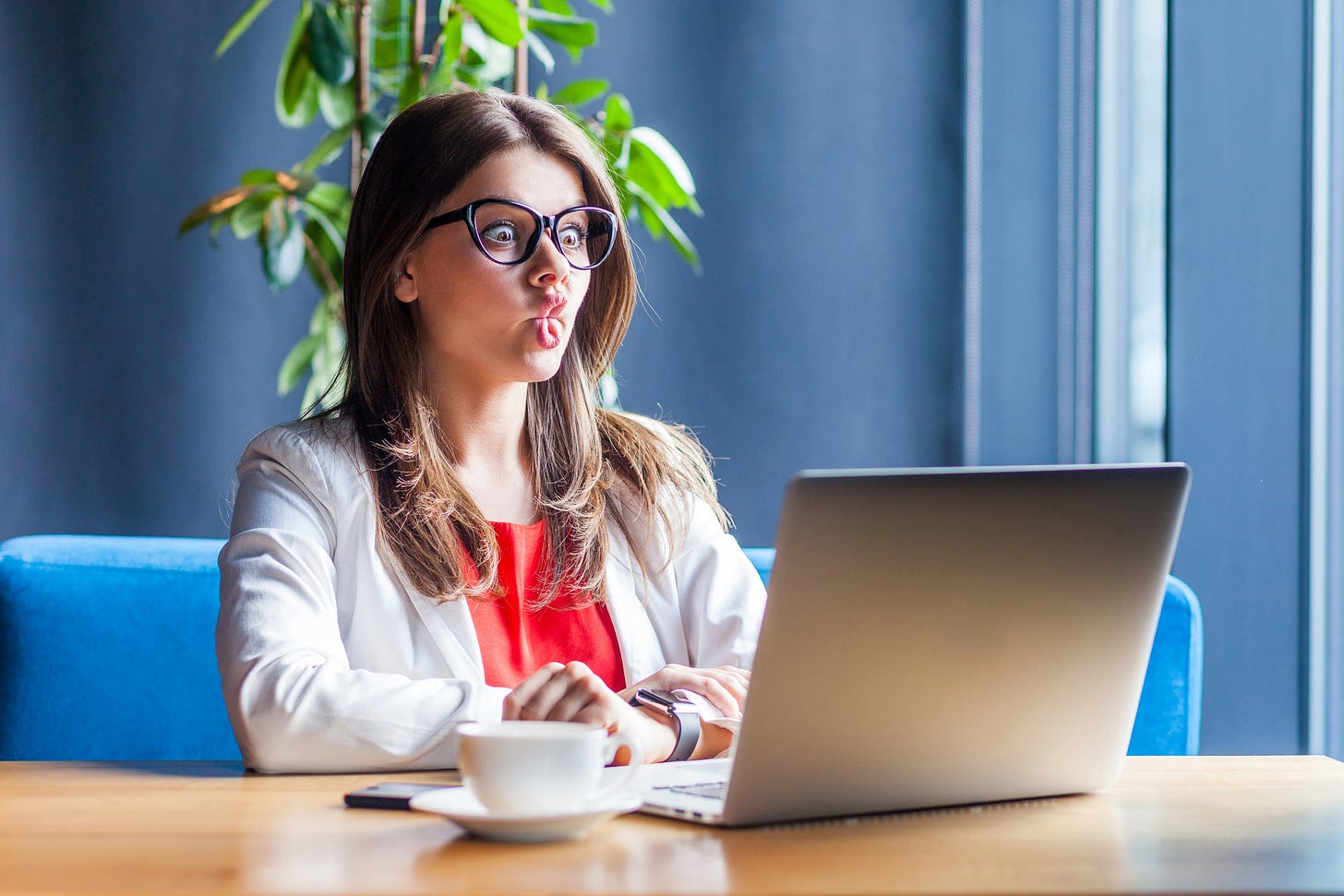 Attractive woman makes crazy face while looking at computer screen