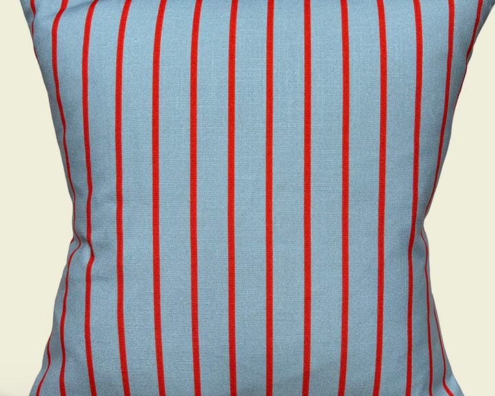 a chequerboard blue rug, a blue and red striped cushion