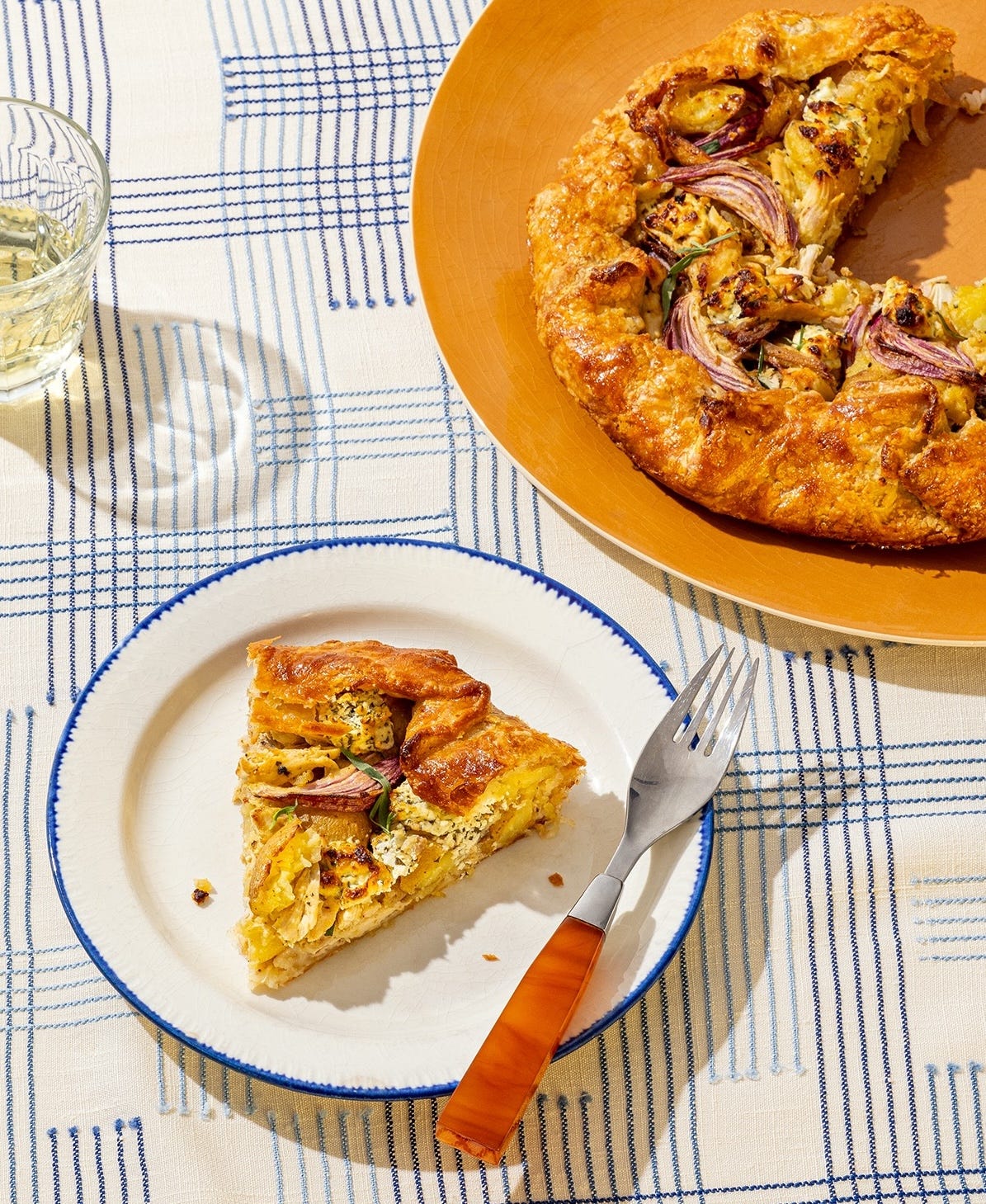 Full galette with a slice on a white plate with blue rim.