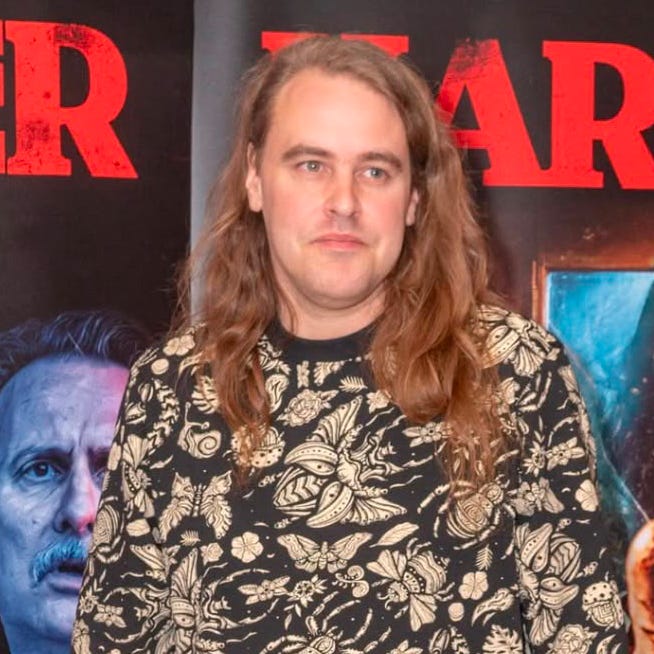 James Crow at a screening of the British supernatural horror film, standing in front of posters showing the film’s glowing-eyed fortune-telling machine and “Death is on the cards” tagline. James Crow at a screening of the British supernatural horror film, standing in front of posters showing the film’s glowing-eyed fortune-telling machine and “Death is on the cards” tagline.