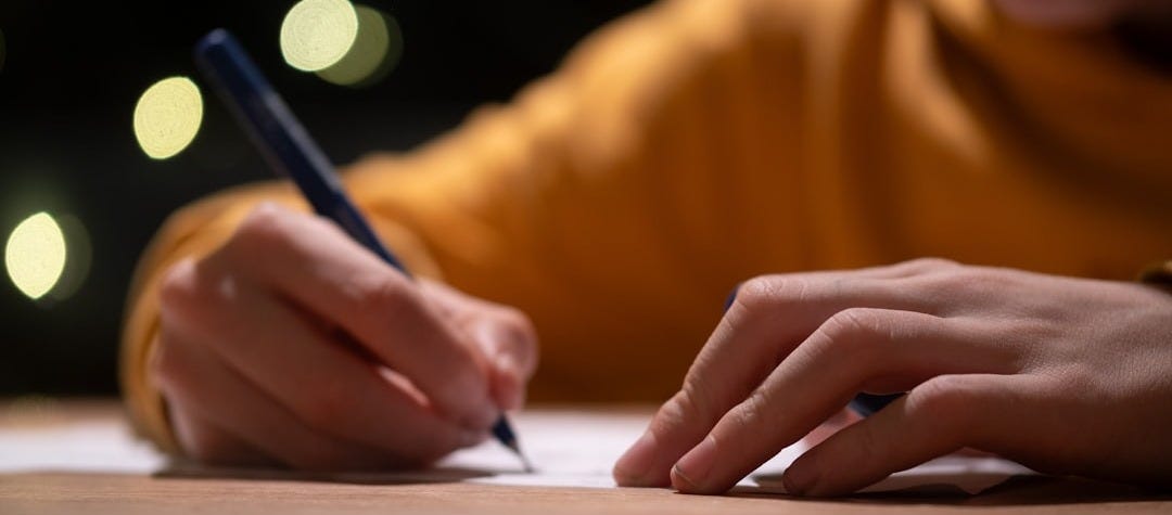 A person writing on a piece of paper with a pen