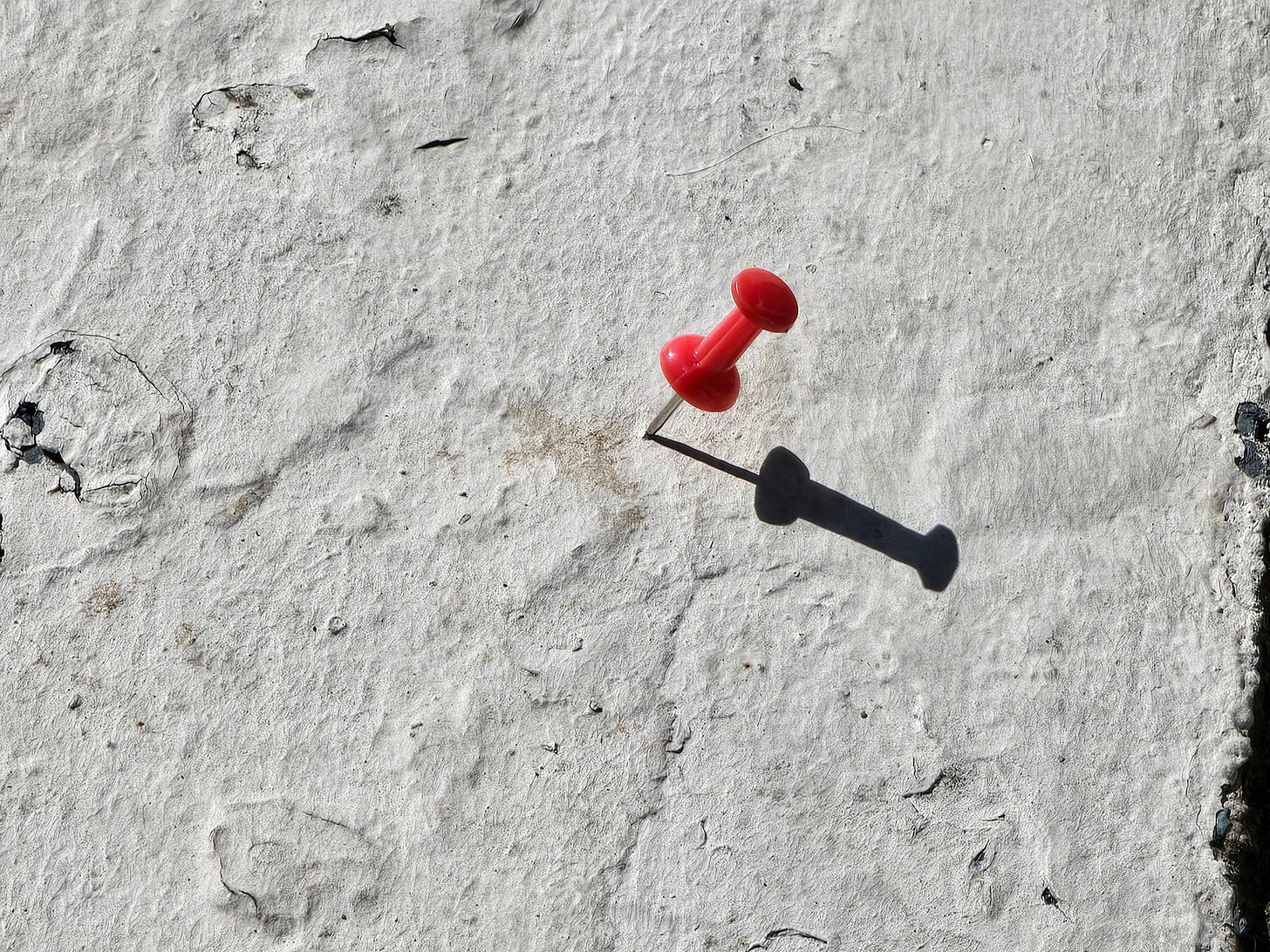 a red push pin stuck in a white curb