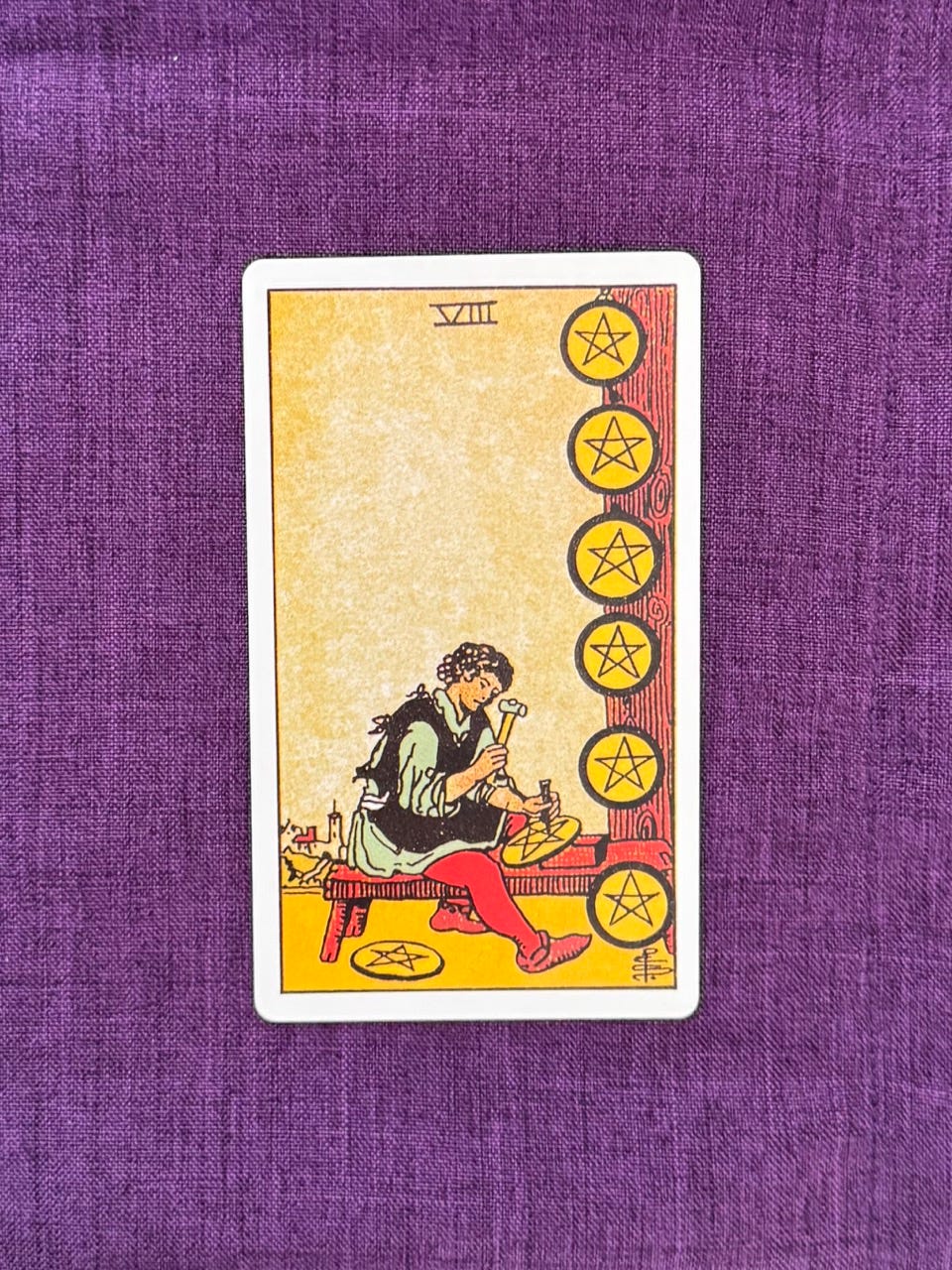 A man is sitting down on a bench, diligently working on his coins with carving tools. 